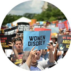 a protest with a person holding a sign that says "women disobey"