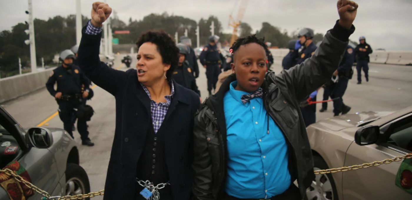A photo from the San Francisco Chronicle showing Kathryn Snyder, left and Nolizwe Nondabula, right, raising their fists as they block traffic during a demonstration against police brutality. The photo was taken on the eastern span of the San Francisco-Oakland Bay Bridge in Oakland, California on January 18, 2016.