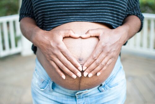 A photo of a pregnant person with their hands resting on their belly